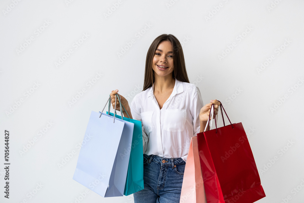 A young woman holds numerous shopping bags on a white background. A young woman holds numerous shopping bags on a white background.