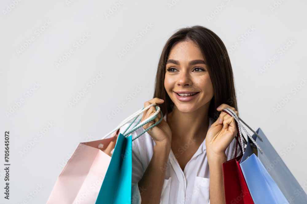 Portrait of a happy young woman holding shopping bags and looking away isolated over white background Portrait of a happy young woman holding shopping bags and looking away isolated over white background