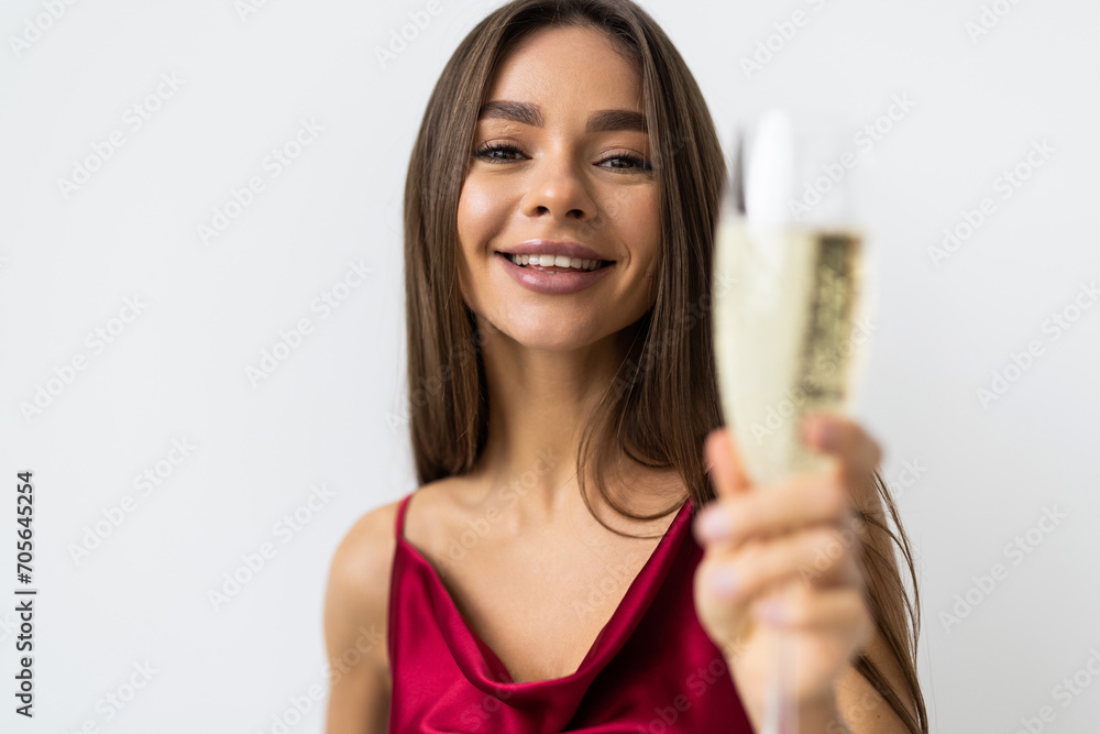 Portrait of a cheerful young woman dressed in red dress holding glass of champagne isolated over white background Portrait of a cheerful young woman dressed in red dress holding glass of champagne isolated over white background