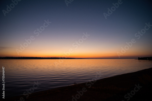 Glowing sky over the lake at dusk. Calm water reflecting the sky after the sunset © andrbk