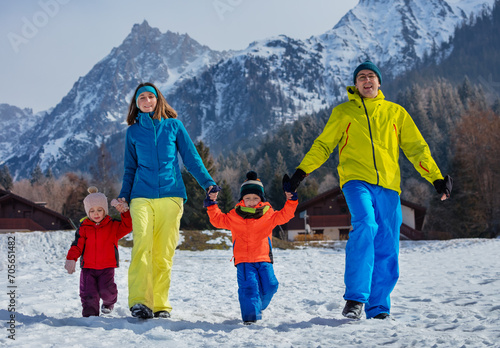 Joyful parents and kids have fun run in snowy sunny mountains