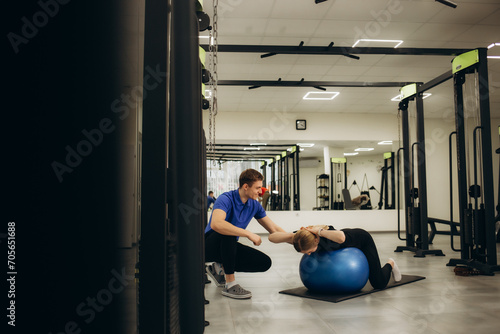 Latin man and woman wearing physiotherapist uniform having rehab session using fit ball at rehab center photo