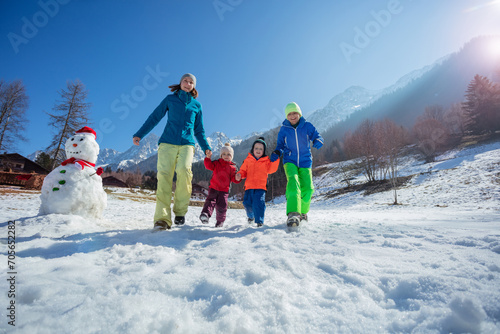 Family bonding running on snowy mountain field in French Alps