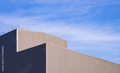 Modern Aluminium Industrial Factory Building with steel fence on rooftop against blue sky background, low angle and perspective side view