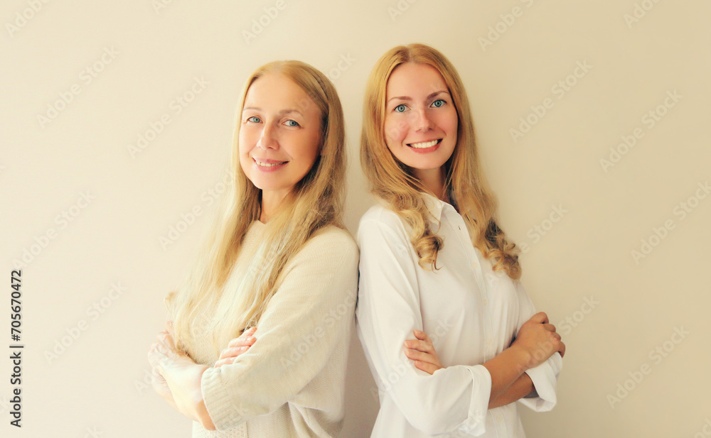Portrait of happy smiling caucasian middle aged mother or sister and adult daughter together on studio background Portrait of happy smiling caucasian middle aged mother or sister and adult daughter together on studio background