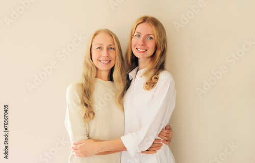 Portrait of happy smiling caucasian middle aged mother or sister and adult daughter together on studio background