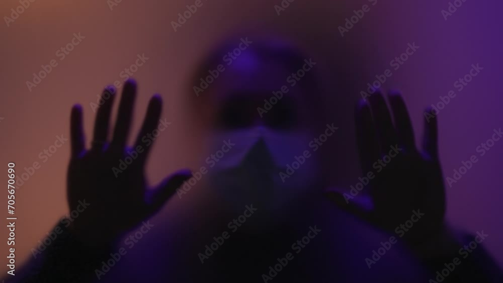 Depression concept.image of man in mask and silhouette of hands behind glass.isolation, loneliness, depression.man places his hands on glass. silhouette behind the glass door. fear of man behind glass Depression concept.image of man in mask and silhouette of hands behind glass.isolation, loneliness, depression.man places his hands on glass. silhouette behind the glass door. fear of man behind glass