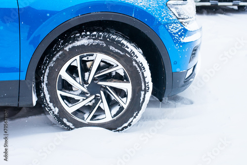 Side view of the front of a blue car on a snowy road during the winter season. © SerPhoto