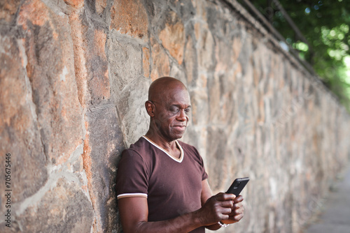 adult man leaning against a wall uses a smartphone