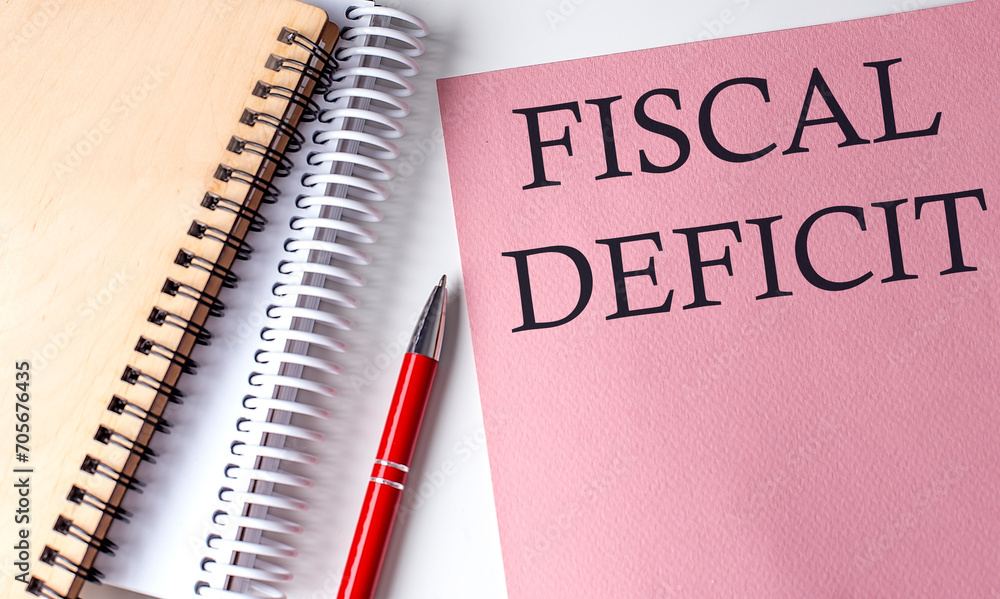 FISCAL DEFICIT word on the pink paper with office tools on white background FISCAL DEFICIT word on the pink paper with office tools on white background
