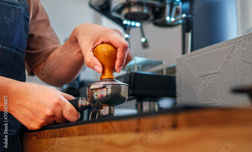 Close-up of hand Barista cafe making coffee with manual presses ground coffee using tamper at the coffee shop photo