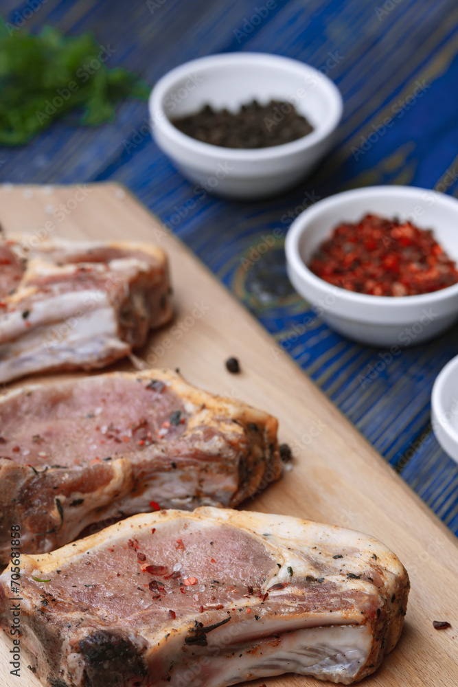 Raw pork ribs with spices and herbs on cutting board on wooden background