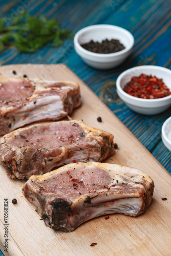 Raw pork ribs with spices and herbs on cutting board on wooden background