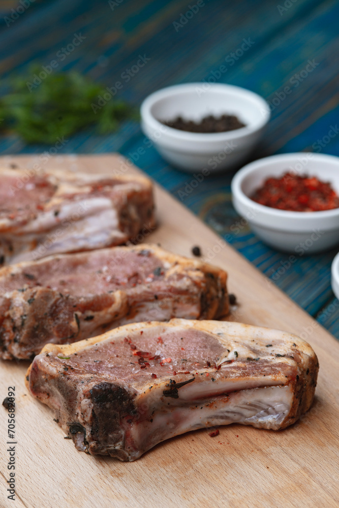 Raw pork ribs with spices and herbs on cutting board on wooden background Raw pork ribs with spices and herbs on cutting board on wooden background