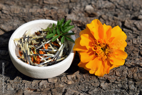 Orange tagetes flower with seeds and leaves in a small bowl  photo
