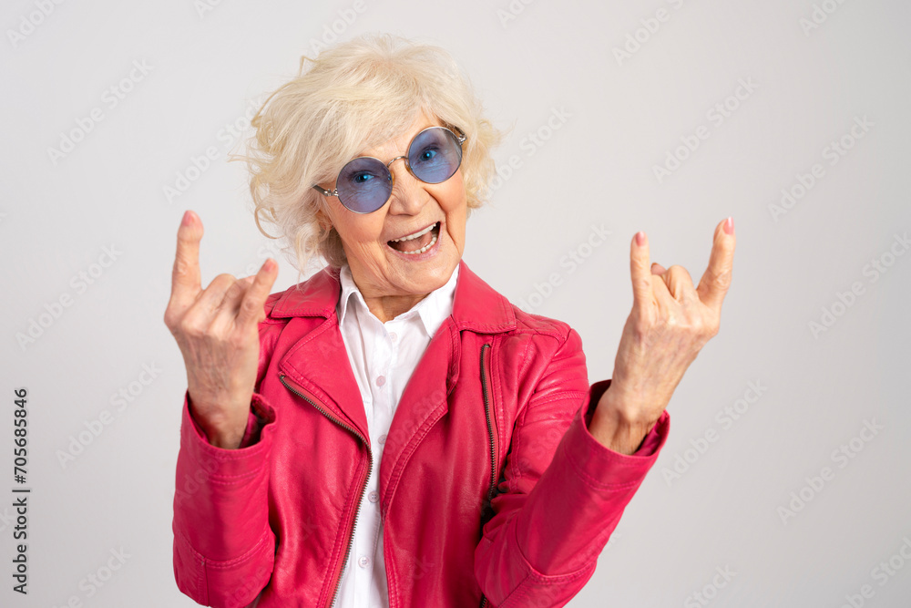 Elderly jouful caucasian woman wearing glasses showing rock gesture