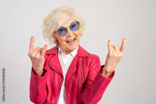 Elderly jouful caucasian woman wearing glasses showing rock gesture