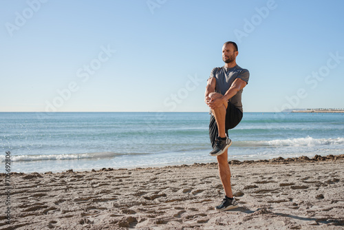 young man does exercises on the beach outdoors (ID: 705692806)