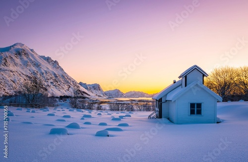 a small church is standing on the snow covered ground in front of mountains photo