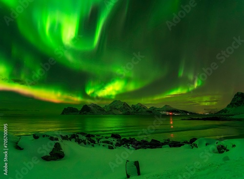 Breathtaking mountain view with vibrant green lights illuminating the night sky © Wirestock