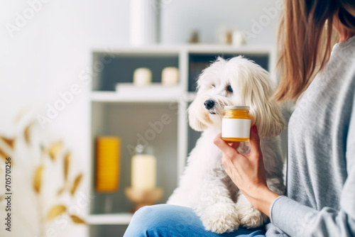 Supplements for pets. Woman with small cute dog holds in her hand medicine jar of animal vitamins against blurred interior. Concept of animal wellness, vitamins for animal, holistic pet health. Mockup photo