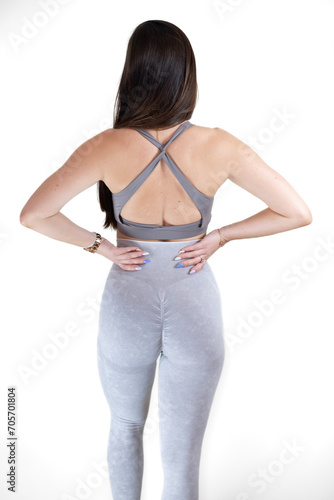 a woman with long black hair standing in yogawear with her hands on her hips photo