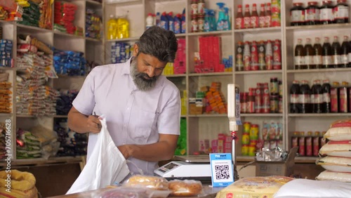 Grocery or kirana store shopkeeper packing groceries - e-commerce delivery  dark store  shopping bag  retail store  online business. Indian shopkeeper working at his shop - home delivery  online bo... photo