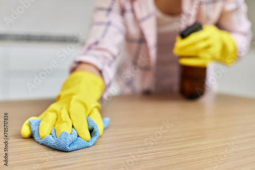 female hands cleaning and wiping wooden table with microfiber cloth. close-up. Housekeeping