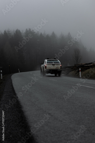 A car in the moody mountains. A car takes a bend in the misty mountain.