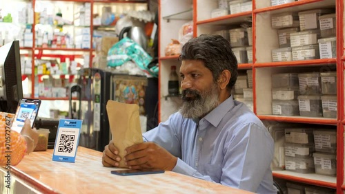 Customer paying money by scanning QR code at the medical shop - cashless payment  contactless transaction  secure payment system. An Indian chemist is receiving digital payments directly into his b...