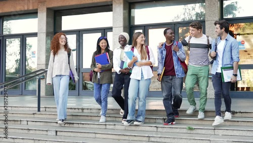 Happy students walking together on university staircase, chatting and laughing outdoors after classes photo