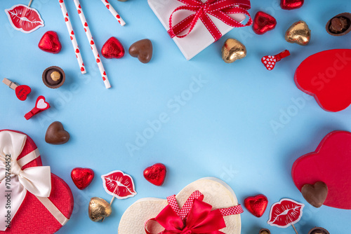 Valentine day celebration, invitation greeting card background with heart shape red, gold candy and chocolate sweets, gift box and on light blue background top view with copy space