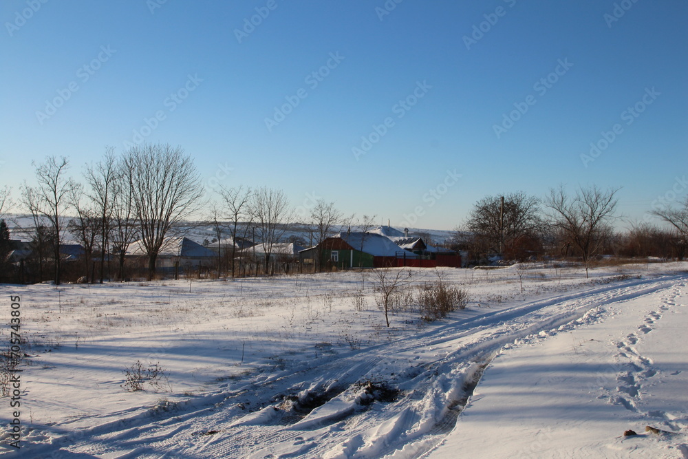 A snowy field with a house and trees in the background