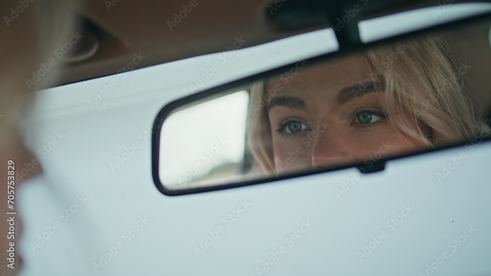 Girl looking automobile mirror enjoying beauty close up. Blonde checking makeup.