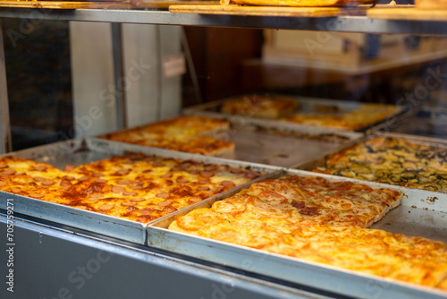 Authentic Italian pizza in a restaurant display window. Various pizzeria in glass window display. Focus on pizza with tomatoes. Food banner