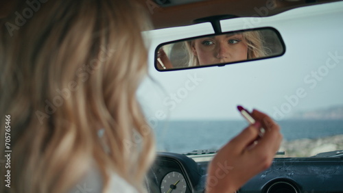 Sexy woman looking car mirror checking makeup closeup. Girl correcting hairstyle