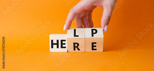 Help is here symbol. Businessman hand Turns cube and changes word Here to Help. Beautiful orange background. Business and Help is here concept. Copy space