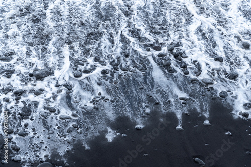 White waves crashing on a black sand beach at madeira island