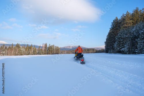 Athlete on a snowmobile moving in the winter forest in the mountains of the Southern Urals