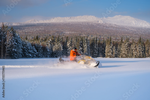 Athlete on a snowmobile moving in the winter forest in the mountains of the Southern Urals