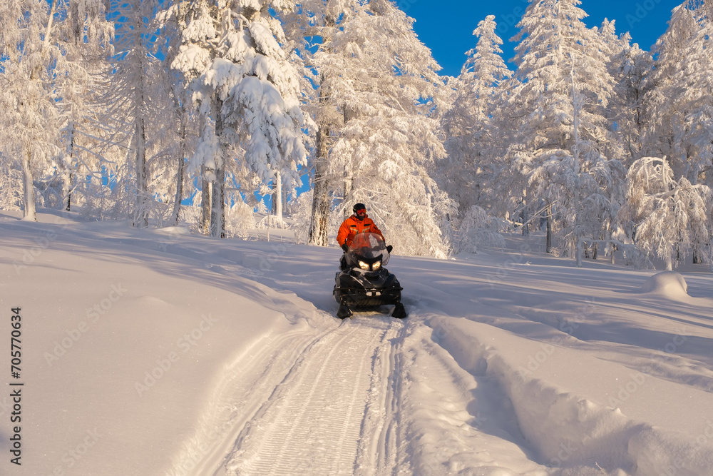 Athlete on a snowmobile moving in the winter forest in the mountains of the Southern Urals Athlete on a snowmobile moving in the winter forest in the mountains of the Southern Urals