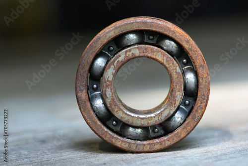 old and rusty ball bearing with grease stain  . rusty bull bearing on wood table . close up  . corrosion of steel photo