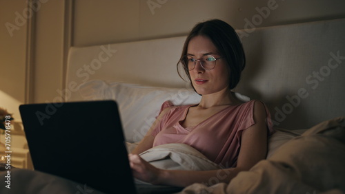 Joyful woman browsing laptop at home night closeup. Smiling girl typing message