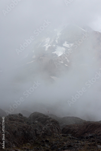 Silhouette of mountain climber in Georgia Caucasus mountains against foggy landscape of mount Kazbek