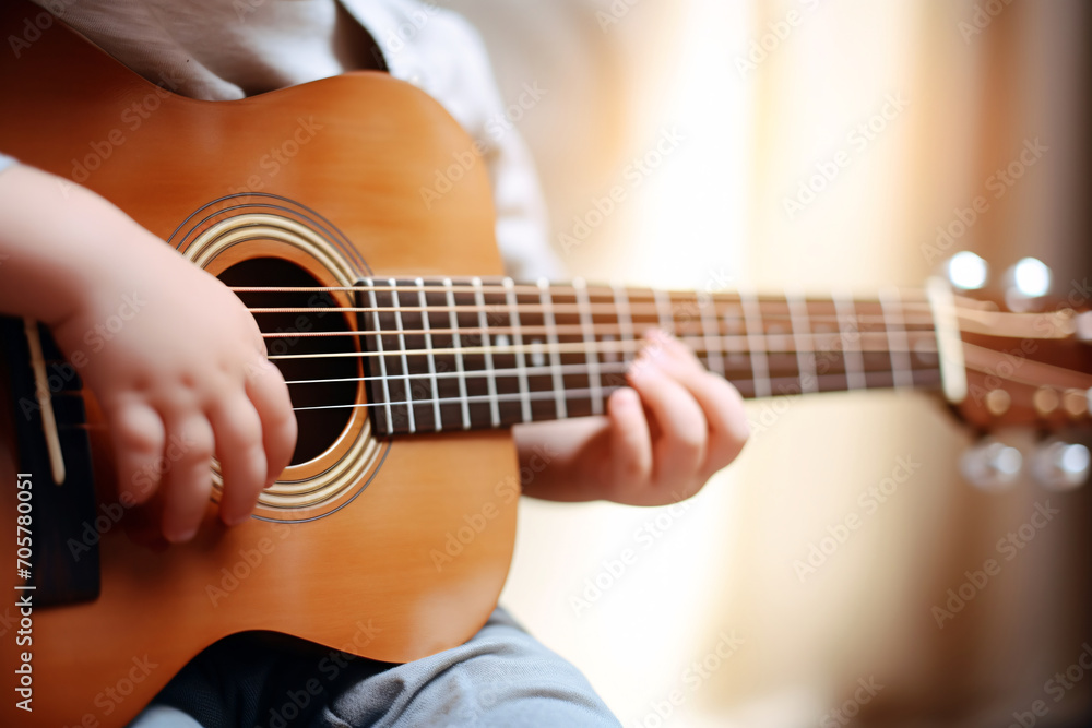 Close up of a child playing guitar. A boy is playing an acoustic guitar. Training in children's mental development. Childhood dreams. Soft focus. Blurry background. Close up of a child playing guitar. A boy is playing an acoustic guitar. Training in children's mental development. Childhood dreams. Soft focus. Blurry background.