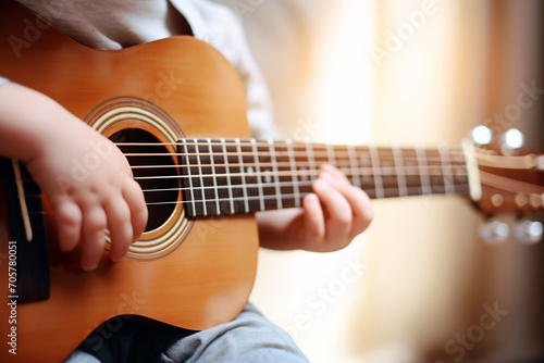 Close up of a child playing guitar. A boy is playing an acoustic guitar. Training in children's mental development. Childhood dreams. Soft focus. Blurry background.