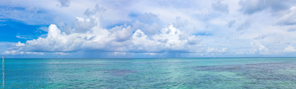 Travel panorama with Caribbean sea and white clouds.