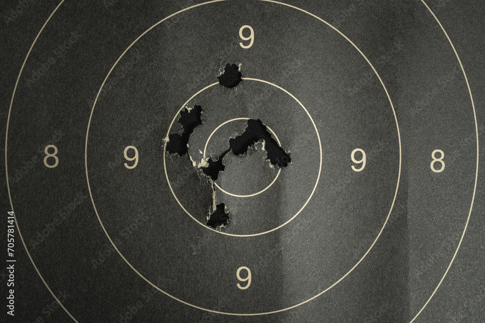 Naklejka premium Paper target with bullet holes in the center, close-up photo.