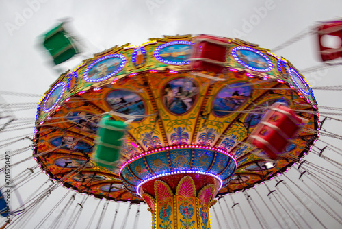 Um brinquedo de rotação em movimento, em um parque de diversões, em um final de tarde nublado.