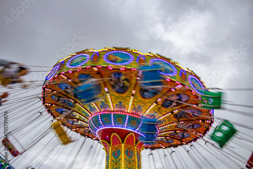 Foto feita com velocidade baixa de um brinquedo de rotação em um parque em um dia nublado com céu cinzento.